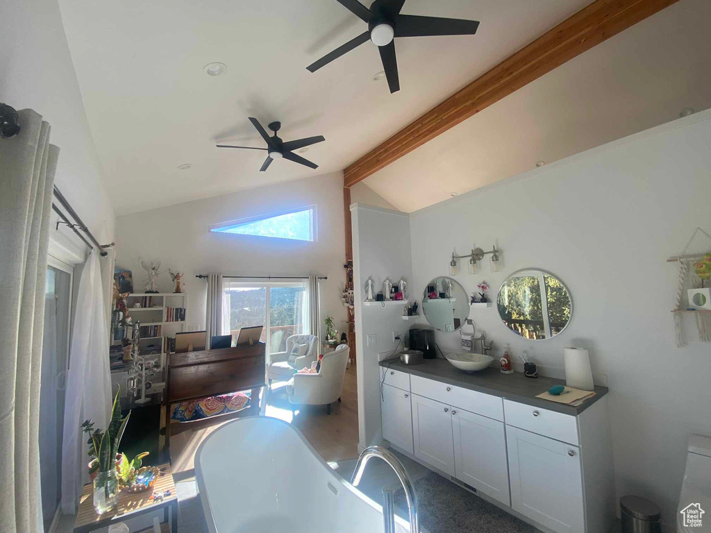 Interior space featuring vaulted ceiling with beams, dark countertops, and a ceiling fan