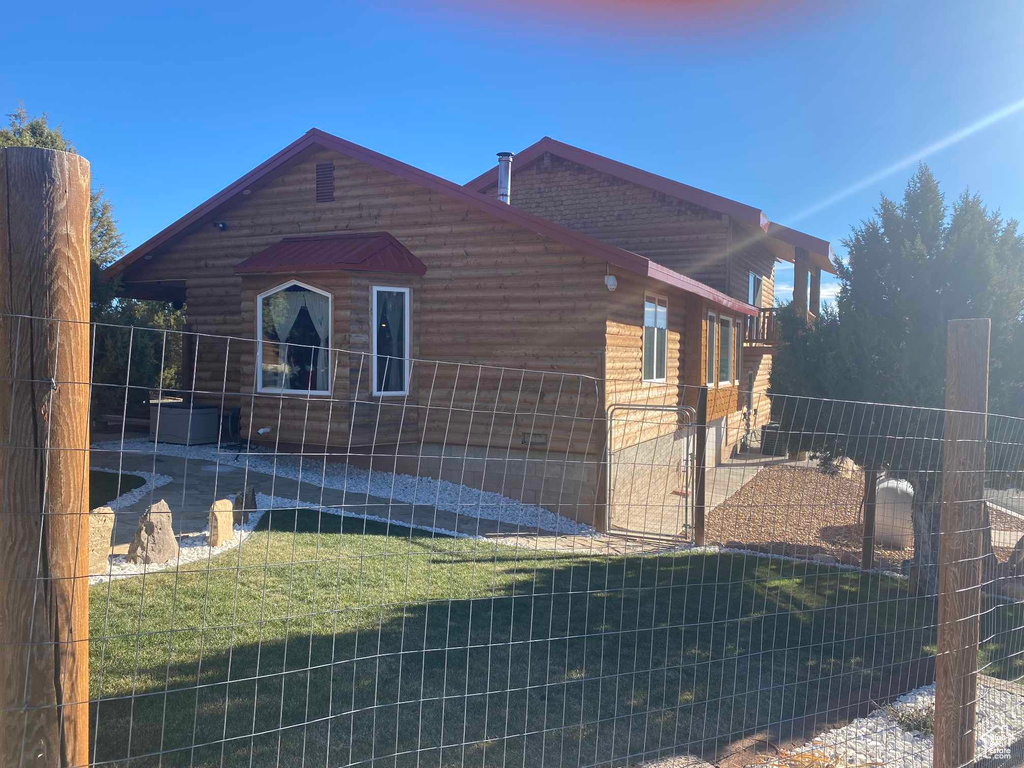 View of side of property with fence, a lawn, and log veneer siding