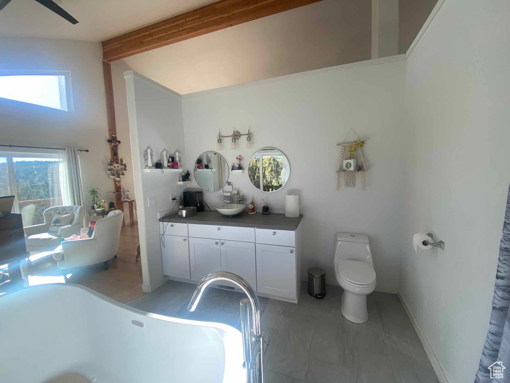 Bathroom featuring high vaulted ceiling, toilet, vanity, a soaking tub, and beamed ceiling