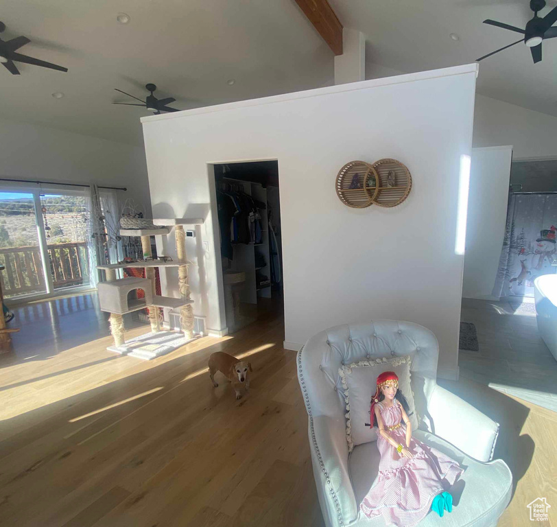 Living room featuring a ceiling fan, lofted ceiling with beams, and wood finished floors