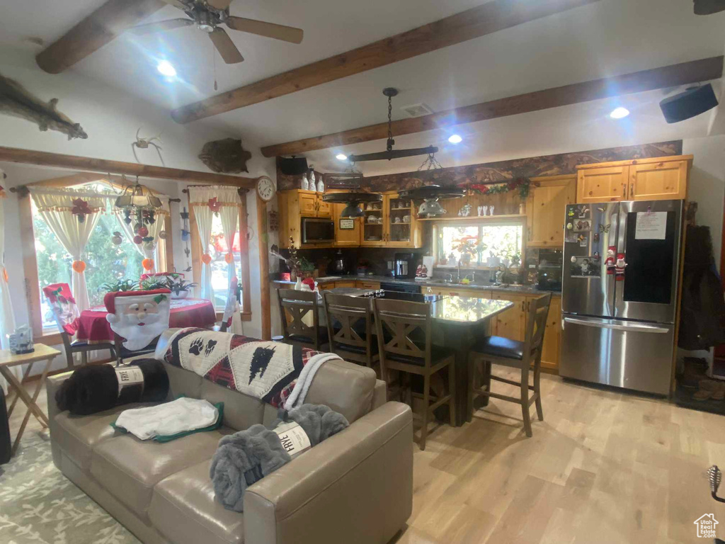 Living area featuring light wood-type flooring, beam ceiling, visible vents, and ceiling fan