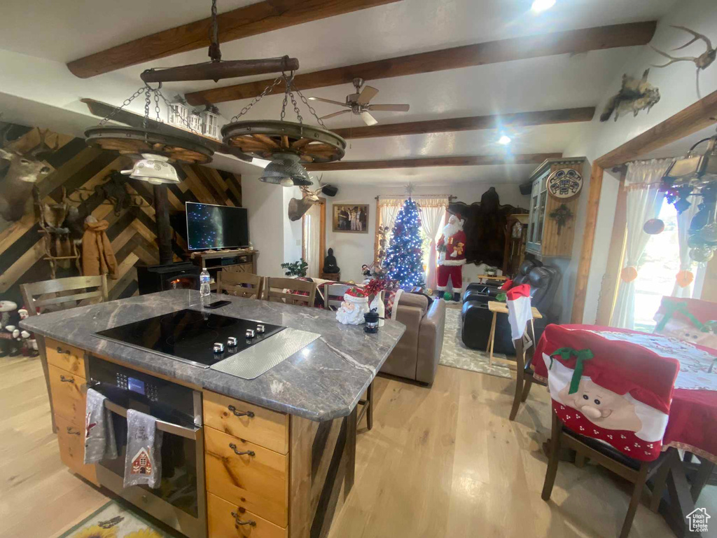 Kitchen featuring a center island, beam ceiling, black electric stovetop, light wood-style flooring, and oven