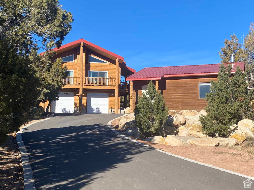 View of front of house with metal roof, driveway, and an attached garage