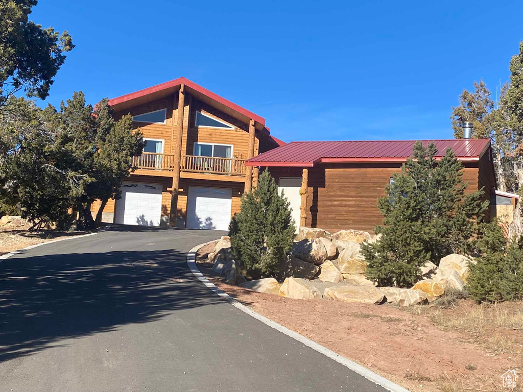 Cabin with aphalt driveway, metal roof, and an attached garage