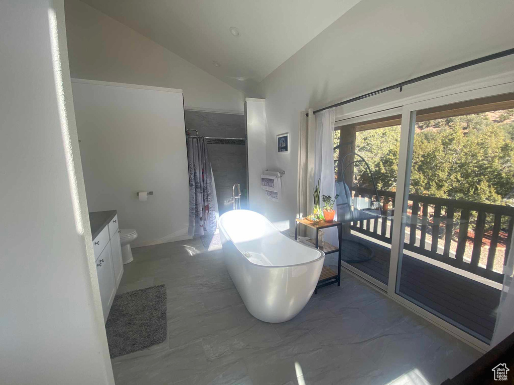 Full bathroom with marble finish floor, lofted ceiling, curtained shower, vanity, and a freestanding tub