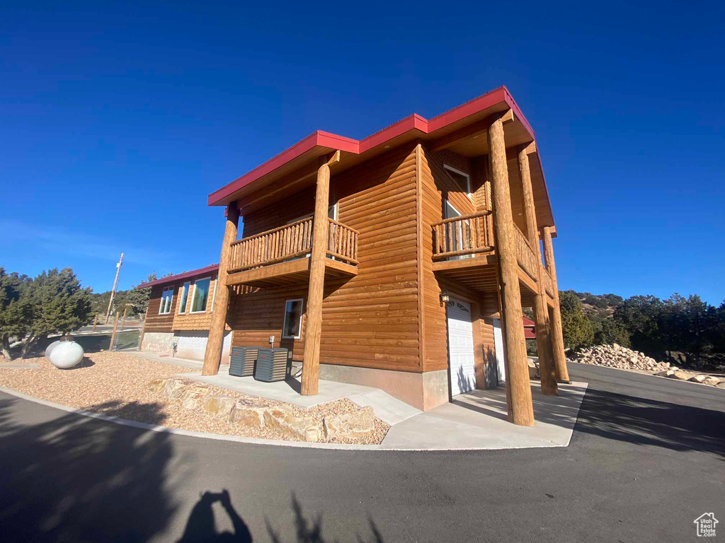 View of front facade featuring faux log siding, a balcony, and an attached garage