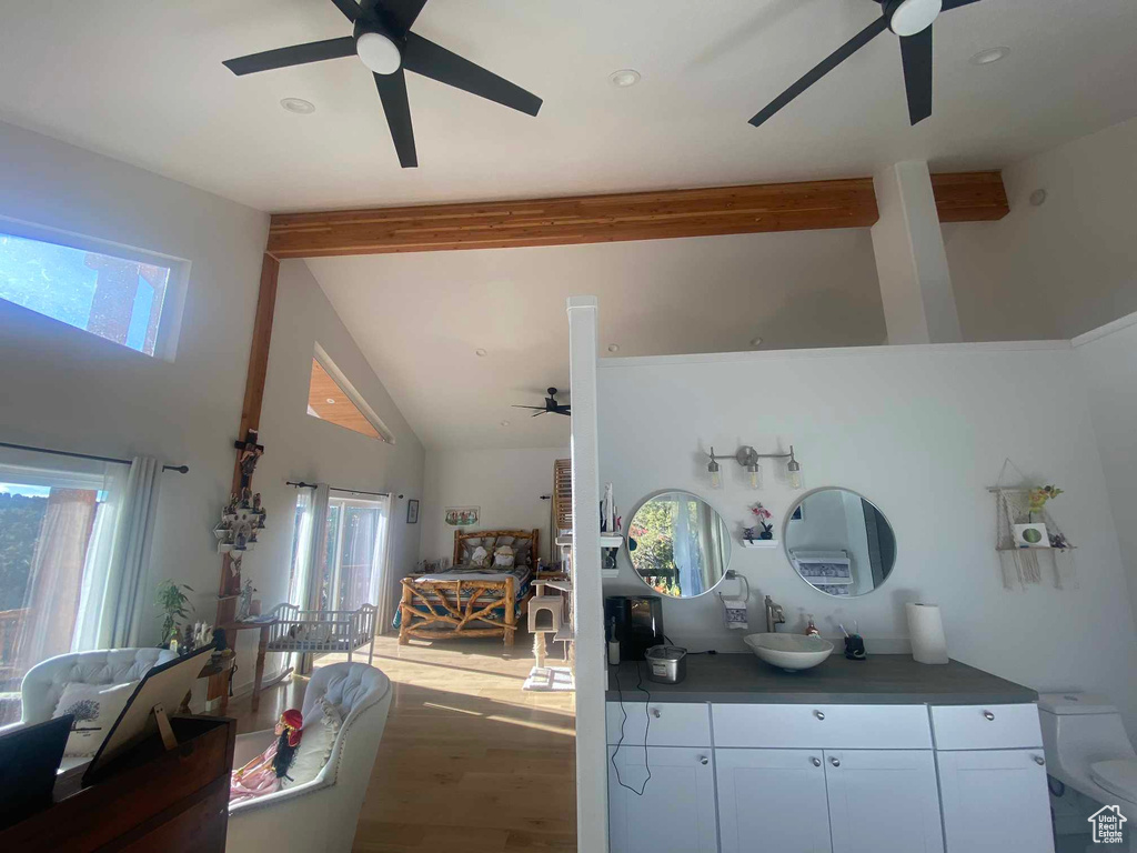 Kitchen featuring ceiling fan, beamed ceiling, wood finished floors, white cabinetry, and a sink