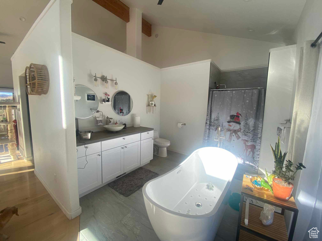 Full bath featuring toilet, vanity, walk in shower, vaulted ceiling, and a freestanding bath