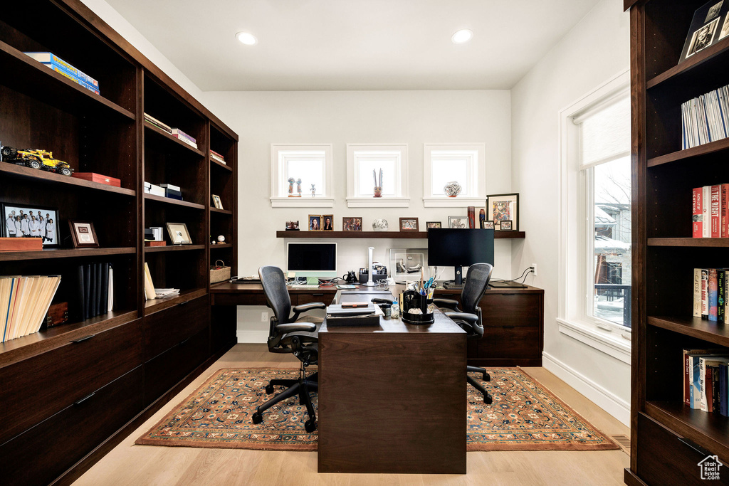 Office area featuring light hardwood / wood-style floors, built in desk, and a healthy amount of sunlight