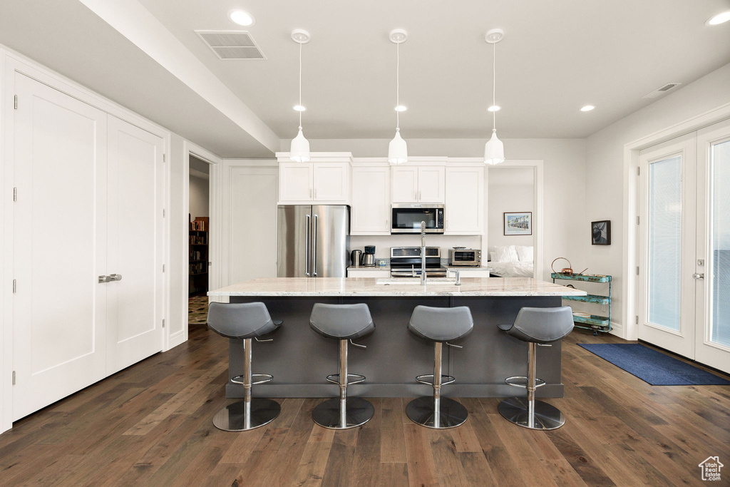 Kitchen with white cabinetry, french doors, stainless steel appliances, and decorative light fixtures