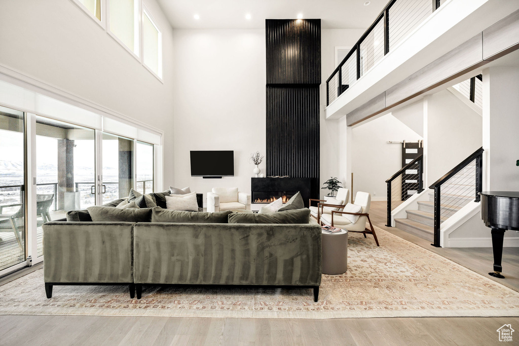 Living room with light hardwood / wood-style floors and a towering ceiling