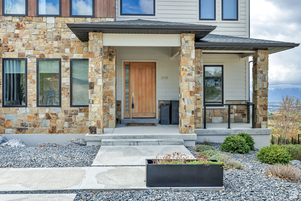 View of exterior entry with covered porch and stone siding
