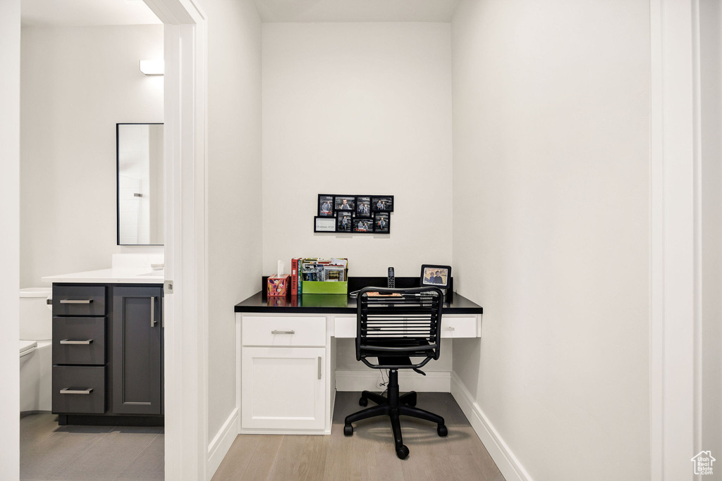 Office space with built in desk and light hardwood / wood-style flooring