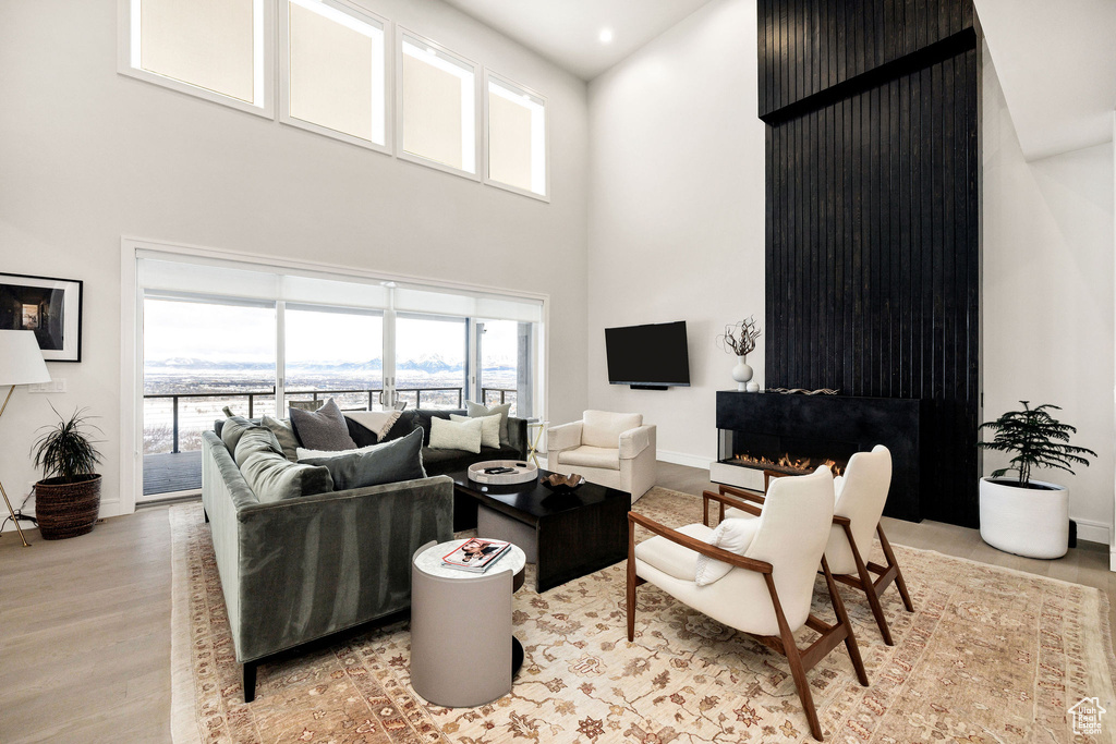 Living room with a towering ceiling and light hardwood / wood-style flooring