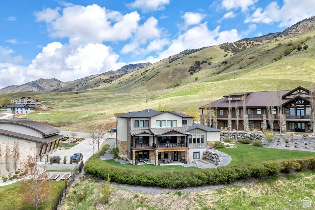 Rear view of house featuring a mountain view, stone siding, and a balcony