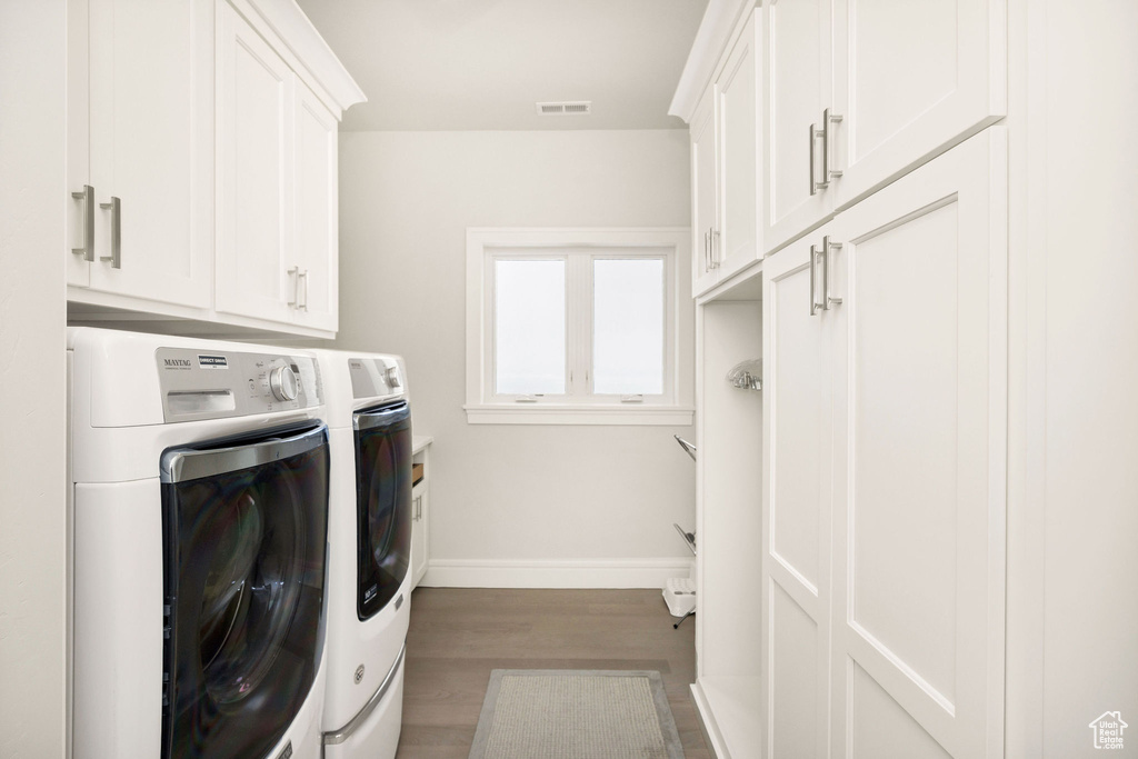 Laundry area with cabinets, washing machine and dryer, and dark hardwood / wood-style floors