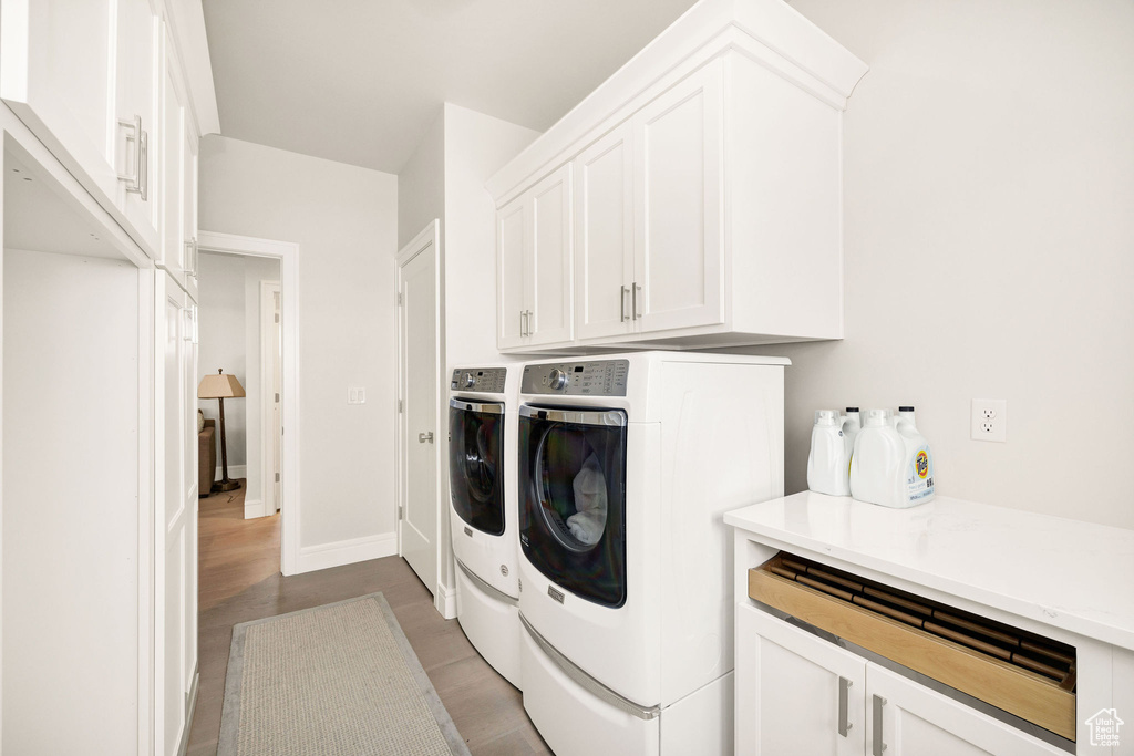 Washroom featuring hardwood / wood-style floors, cabinets, and washer and clothes dryer
