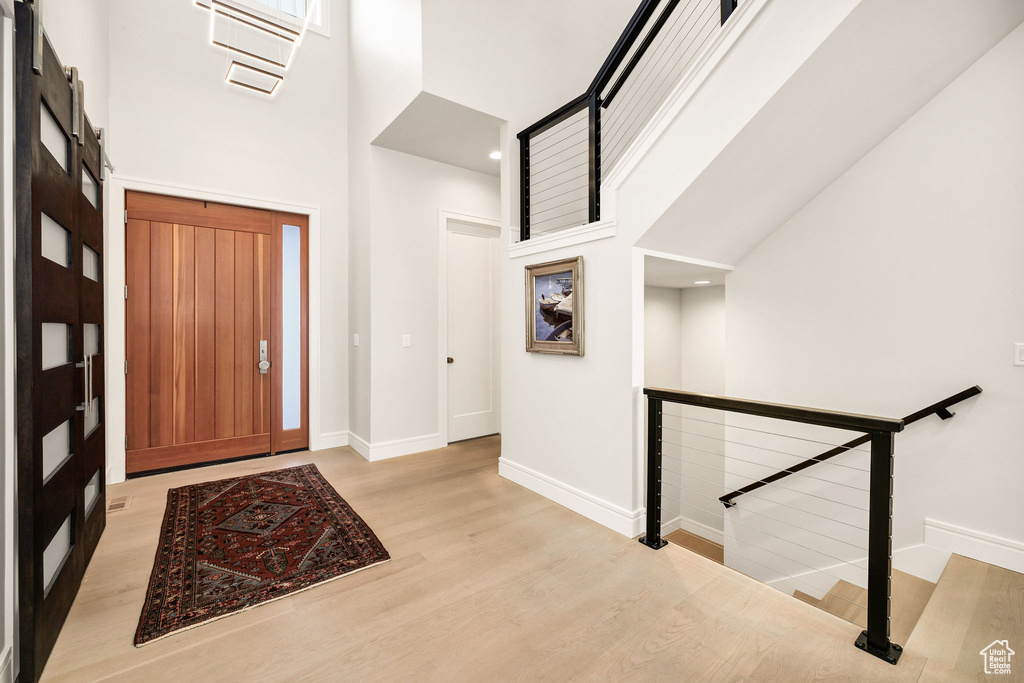Entrance foyer with a barn door, a high ceiling, and light hardwood / wood-style flooring