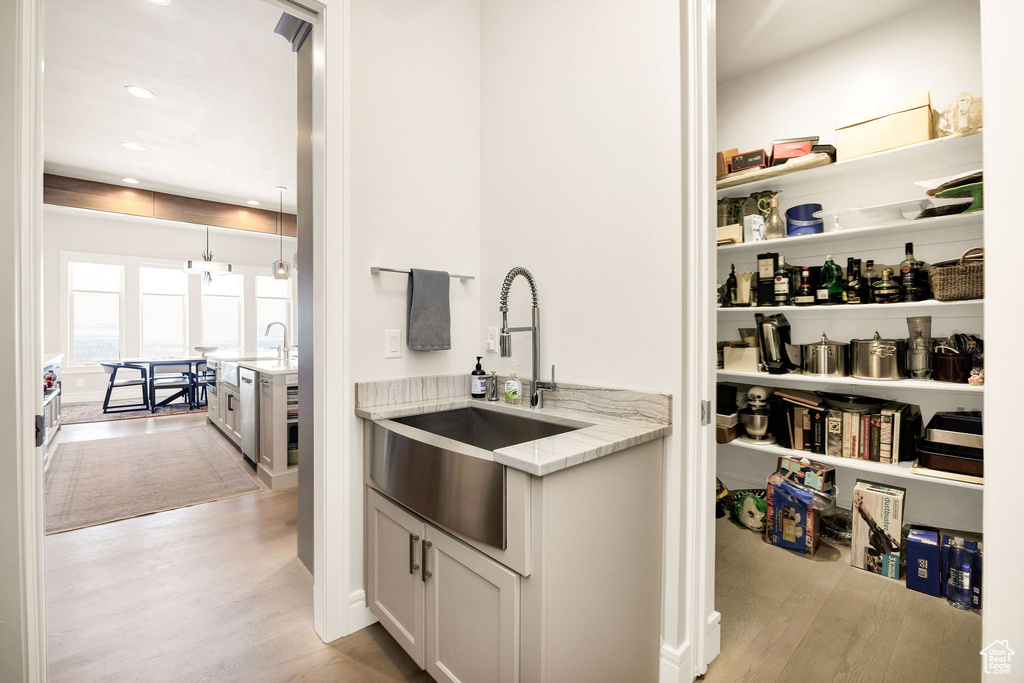 Interior space with white cabinetry, light hardwood / wood-style flooring, sink, and light stone countertops