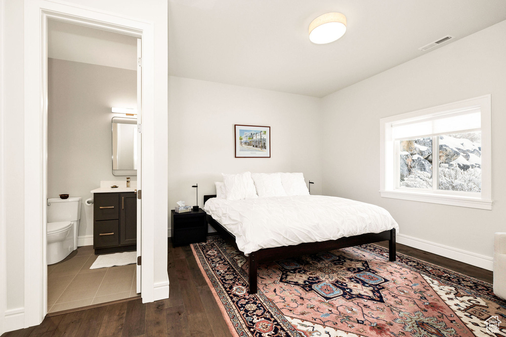 Bedroom with dark wood-type flooring and ensuite bath