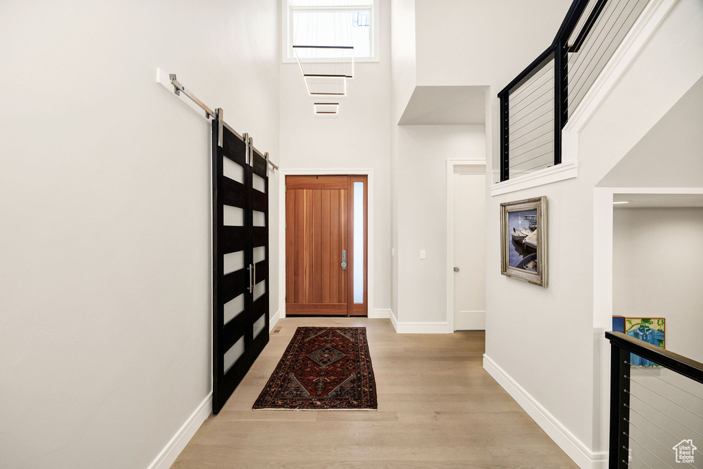 Foyer featuring light hardwood / wood-style floors, a barn door, and a towering ceiling