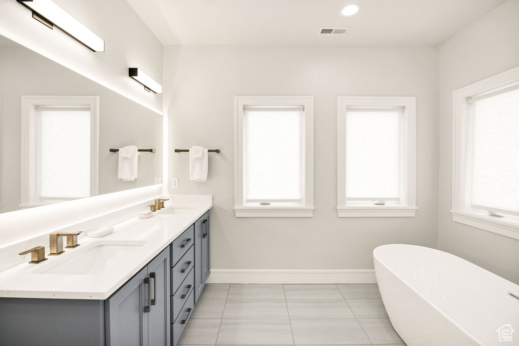Bathroom with vanity, a washtub, and tile patterned floors