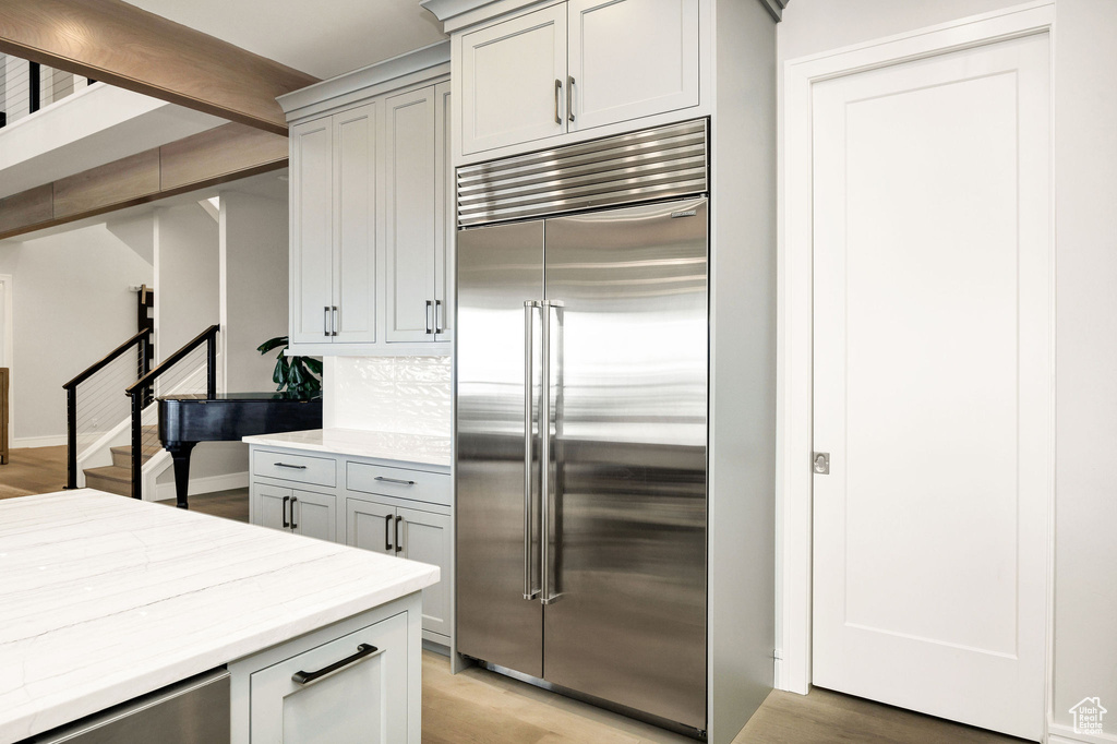 Kitchen with light hardwood / wood-style floors, tasteful backsplash, gray cabinetry, and built in fridge