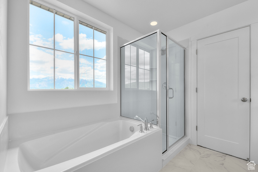 Bathroom with marble finish floors, a garden tub, a shower stall, and recessed lighting