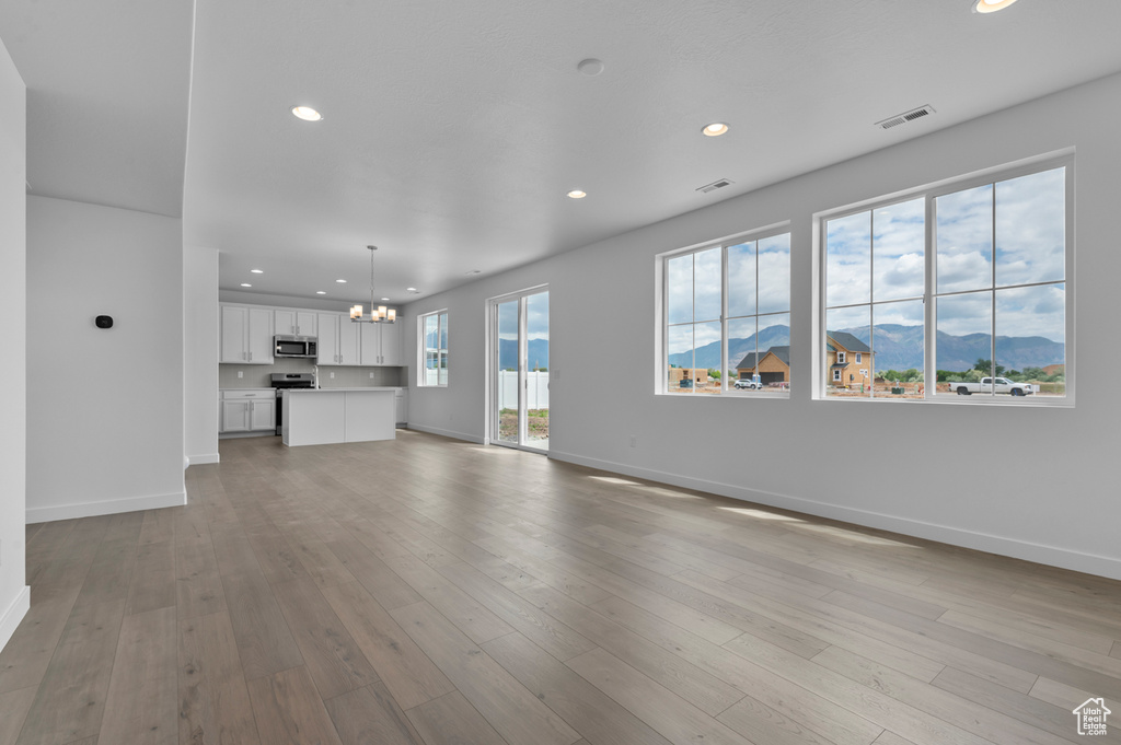 Unfurnished living room featuring a chandelier, a mountain view, recessed lighting, and baseboards