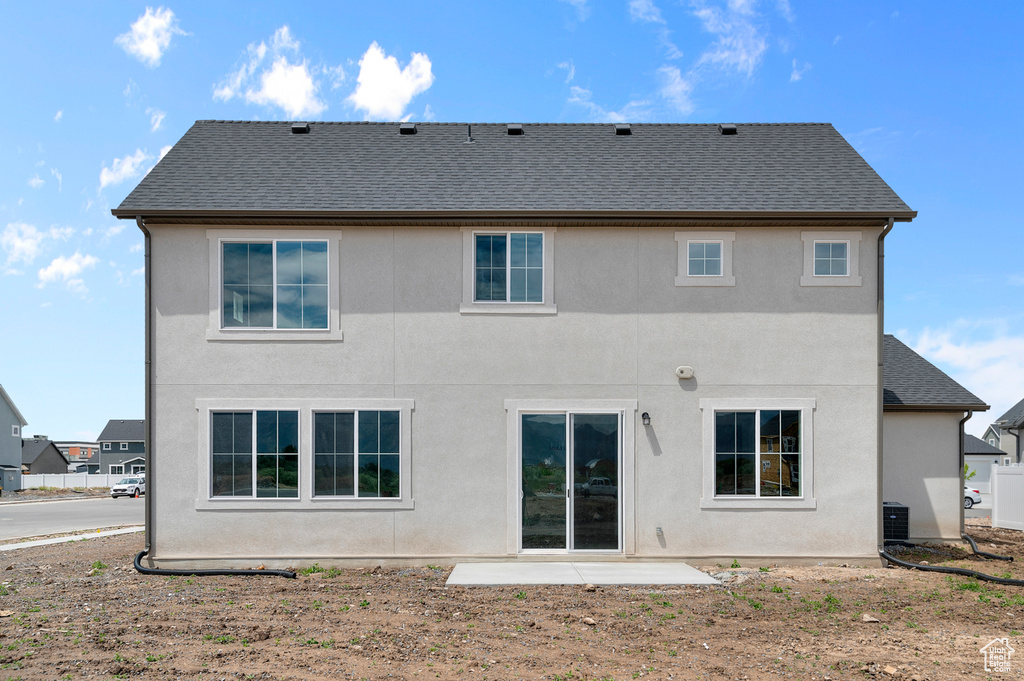 Back of property with stucco siding, a shingled roof, and a patio area