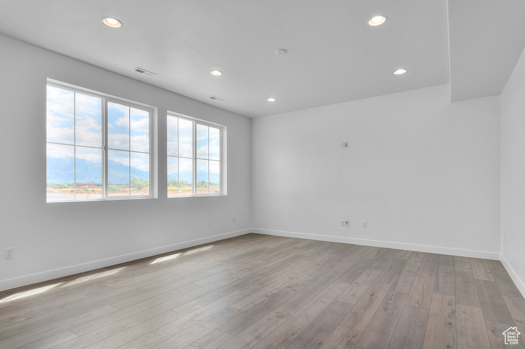 Empty room featuring recessed lighting, baseboards, and wood-type flooring