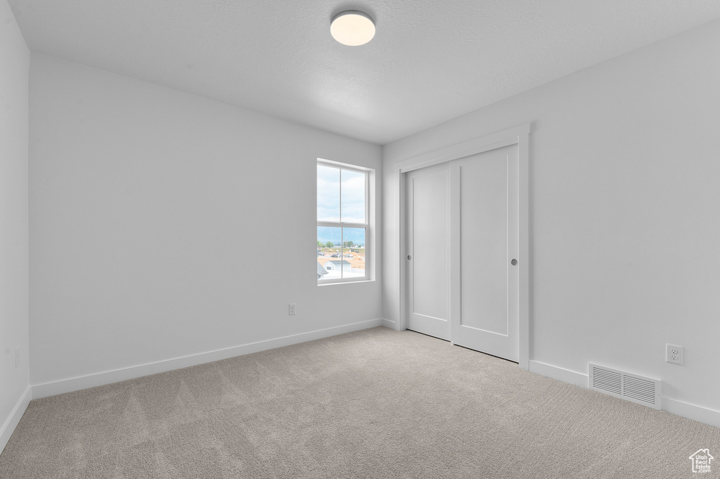Unfurnished bedroom featuring carpet flooring, baseboards, and a closet