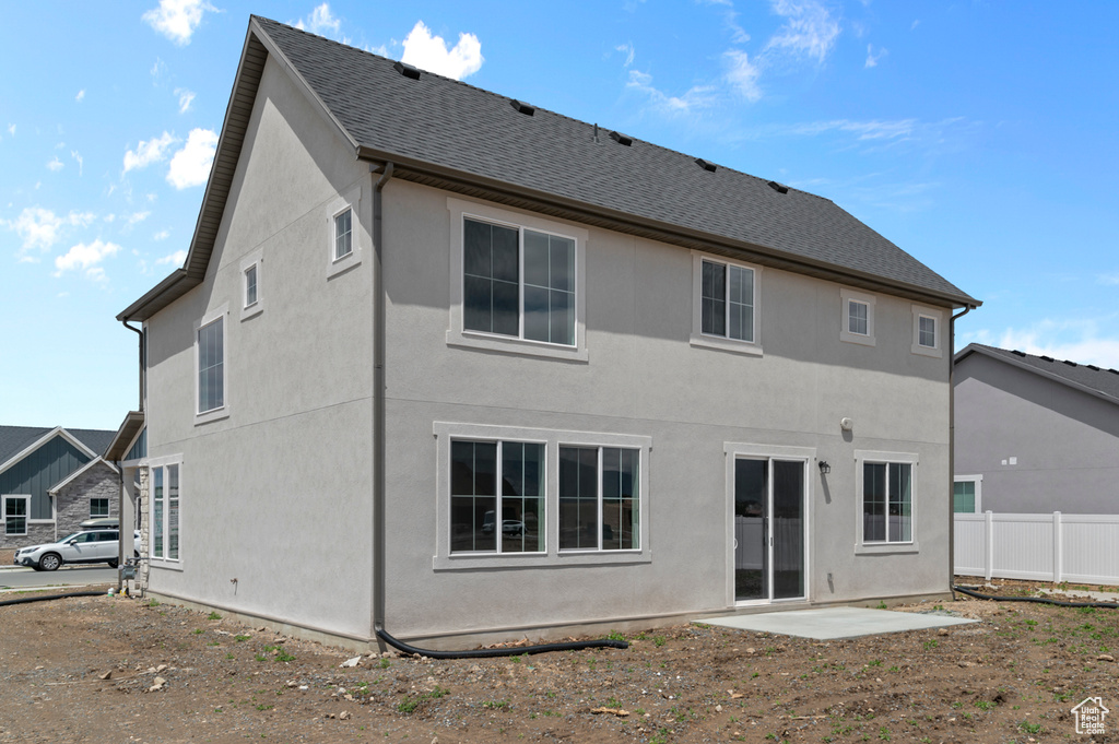 Rear view of house featuring stucco siding and a shingled roof