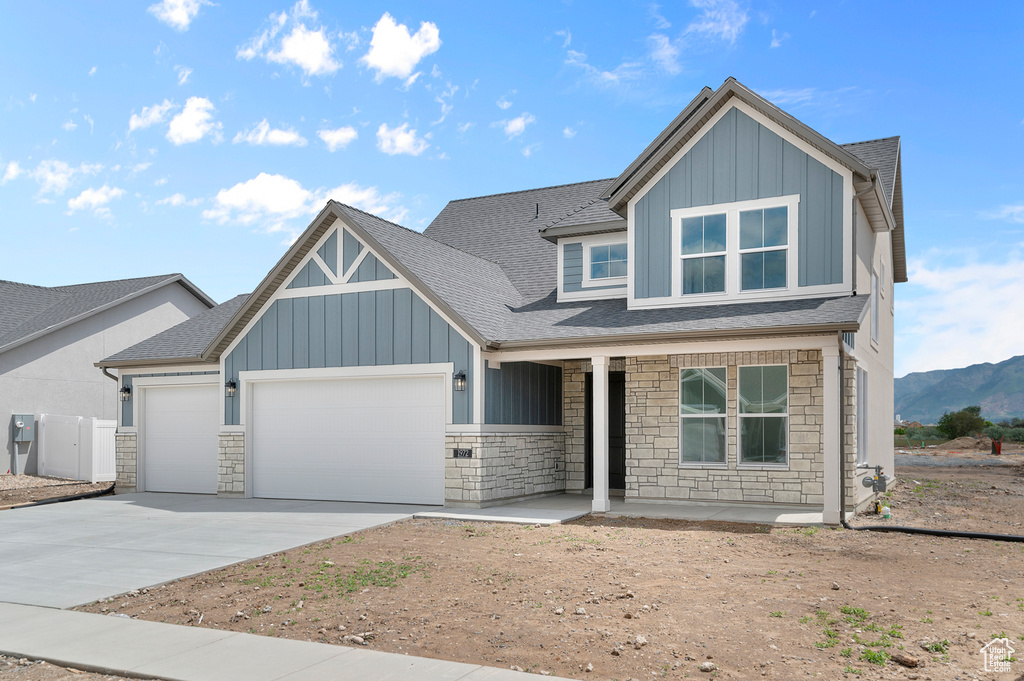View of front facade with stone siding, an attached garage, a porch, and board and batten siding
