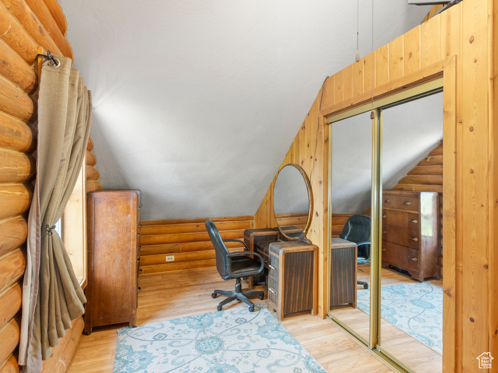 Office featuring rustic walls, light hardwood / wood-style flooring, and lofted ceiling