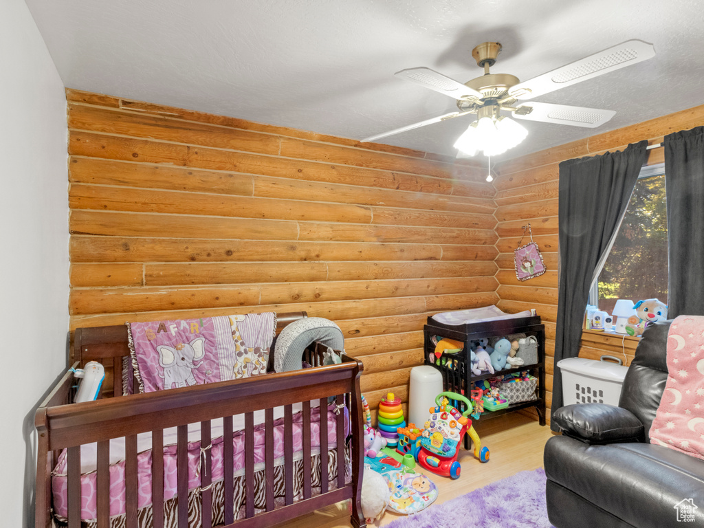 Bedroom featuring hardwood / wood-style flooring, ceiling fan, and log walls