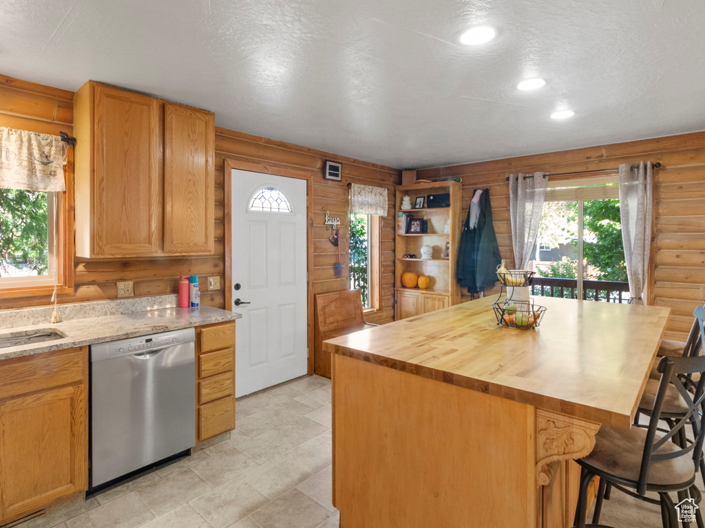 Kitchen featuring stainless steel dishwasher, log walls, a center island, and a breakfast bar