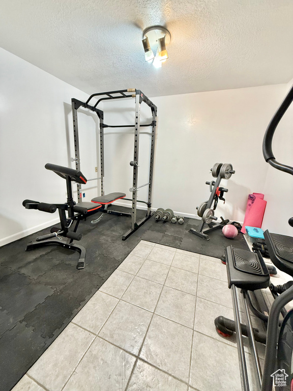 Workout room with a textured ceiling and baseboards