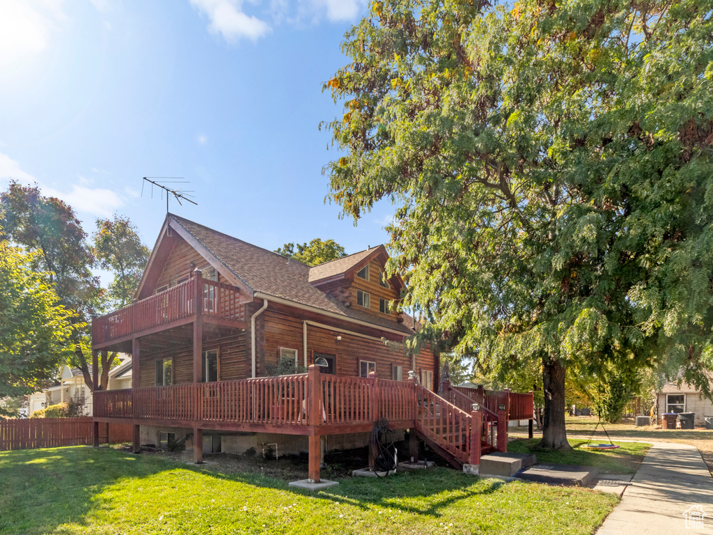 View of side of home featuring a wooden deck and a lawn