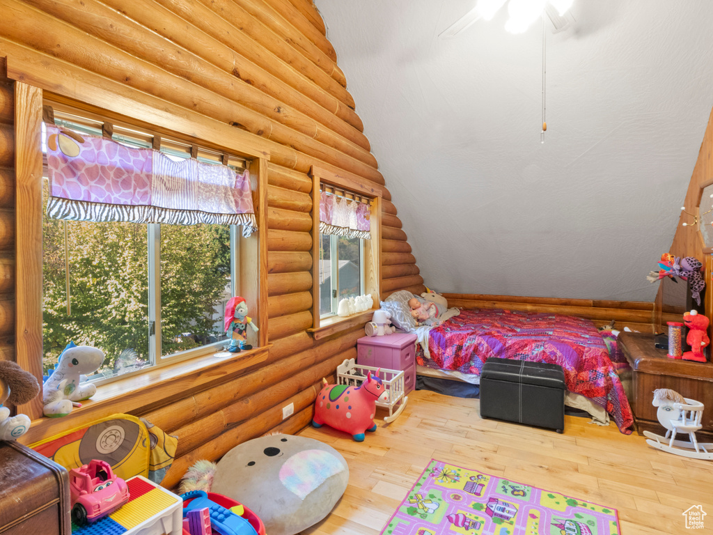 Bedroom featuring vaulted ceiling, hardwood / wood-style floors, and log walls