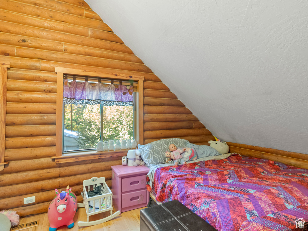 Bedroom featuring hardwood / wood-style floors and log walls