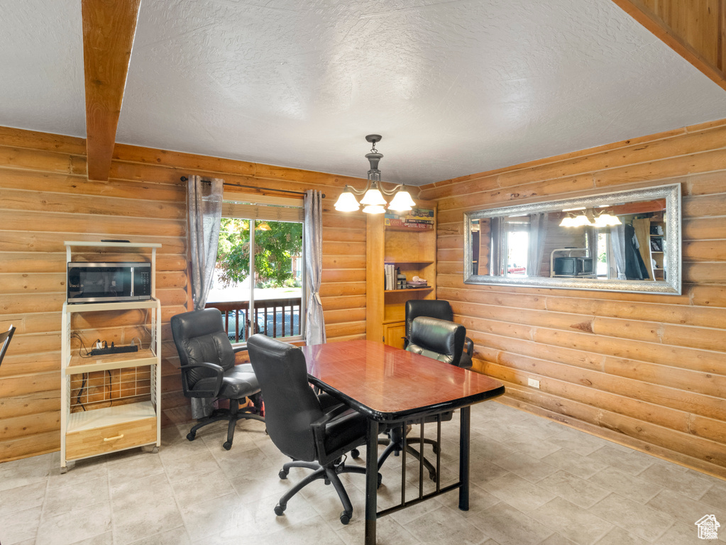 Office featuring a textured ceiling, rustic walls, beam ceiling, and a notable chandelier