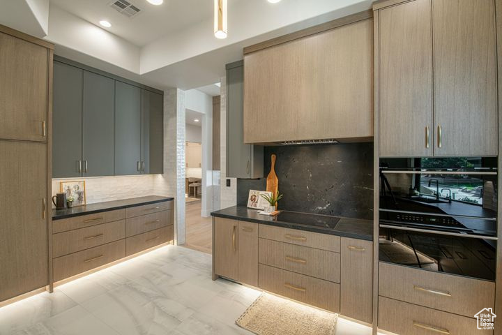 Kitchen featuring gray cabinets, black appliances, tasteful backsplash, and light brown cabinetry