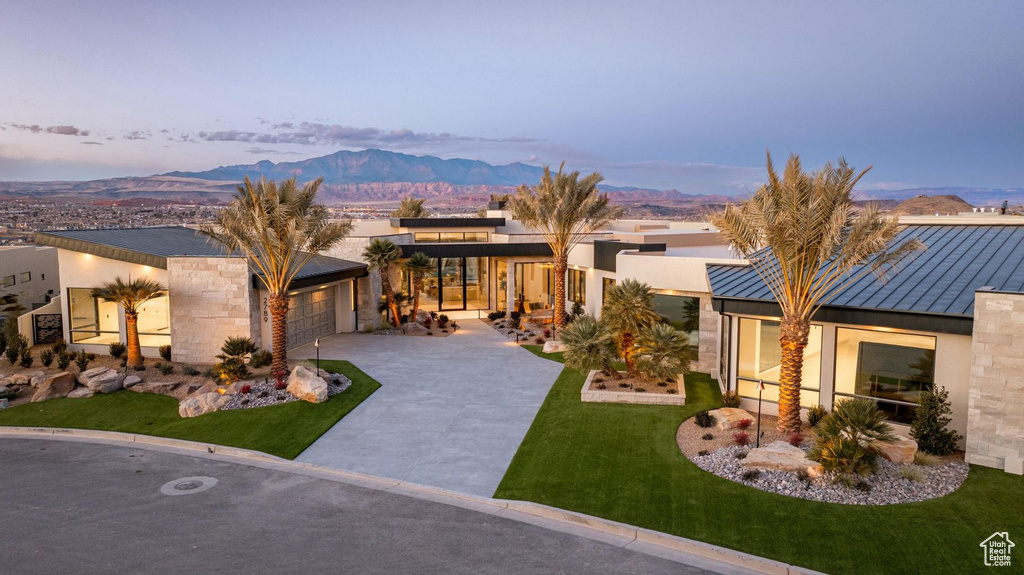 View of front of house with a mountain view, a garage, and a lawn