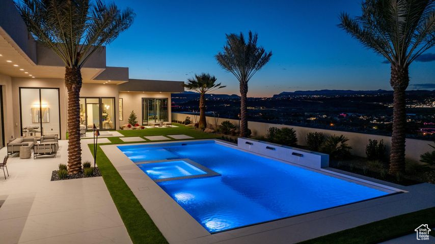 Pool at dusk featuring a patio area and an in ground hot tub