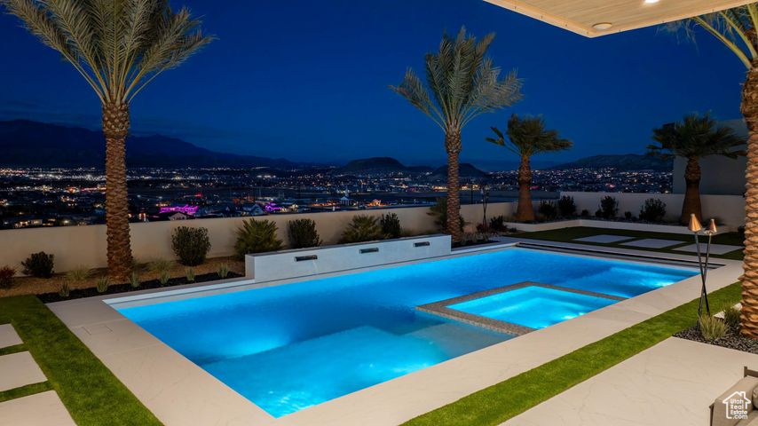 Pool at twilight featuring an in ground hot tub and a water view