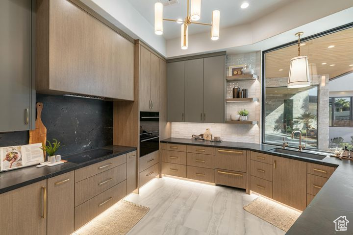 Kitchen with hanging light fixtures, sink, backsplash, black electric cooktop, and light brown cabinetry