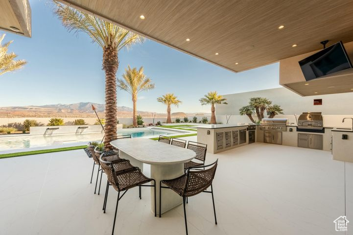 View of patio / terrace with a mountain view, a bar, an outdoor kitchen, area for grilling, and a fenced in pool