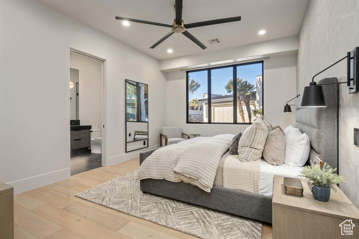 Bedroom featuring ceiling fan, light wood-type flooring, and ensuite bath