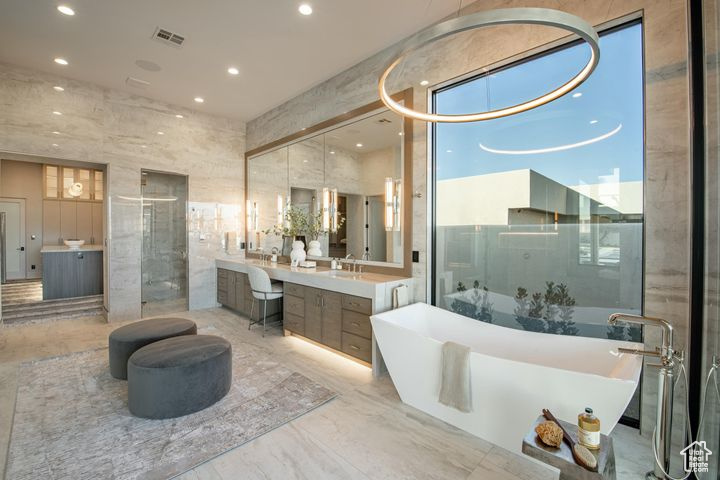 Bathroom featuring tile walls, a tub to relax in, and vanity